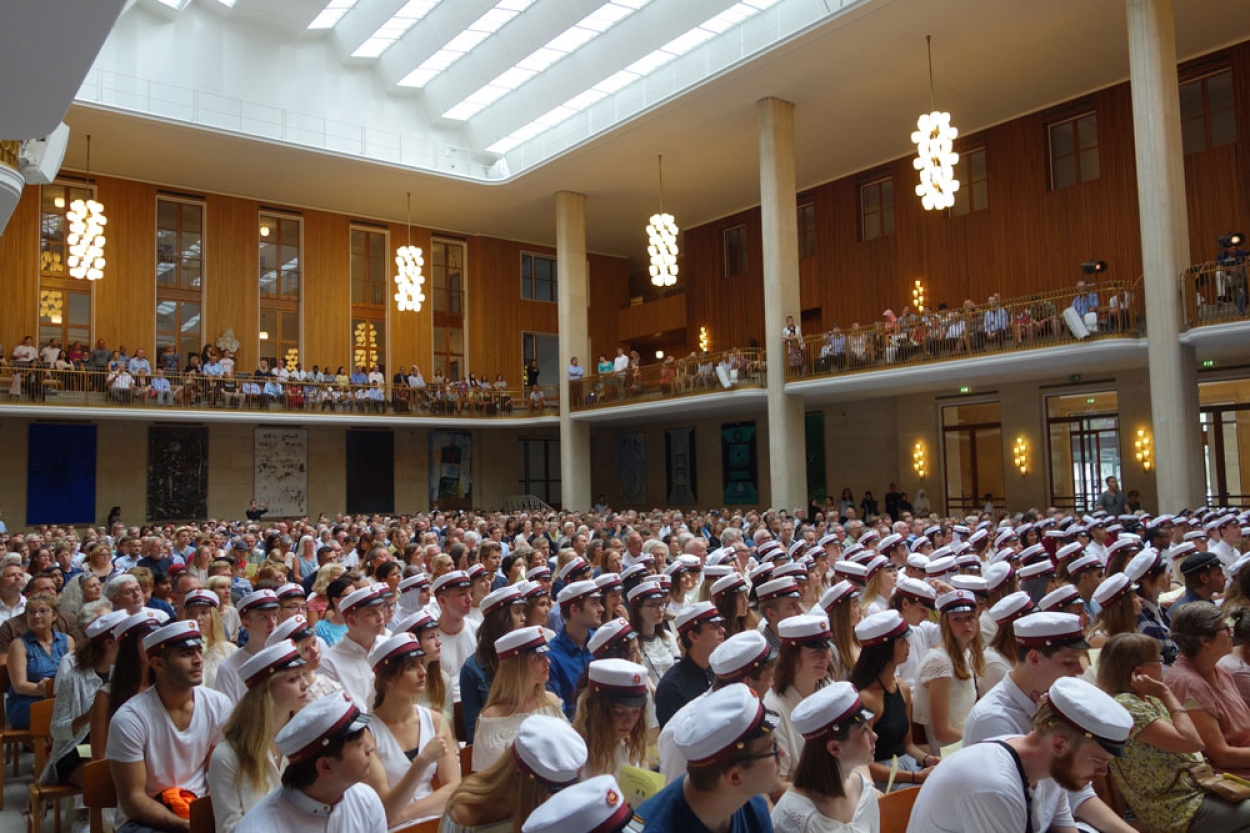 Foto af studenter med huer, der sidder i Frederiksberg Rådhus festsal.